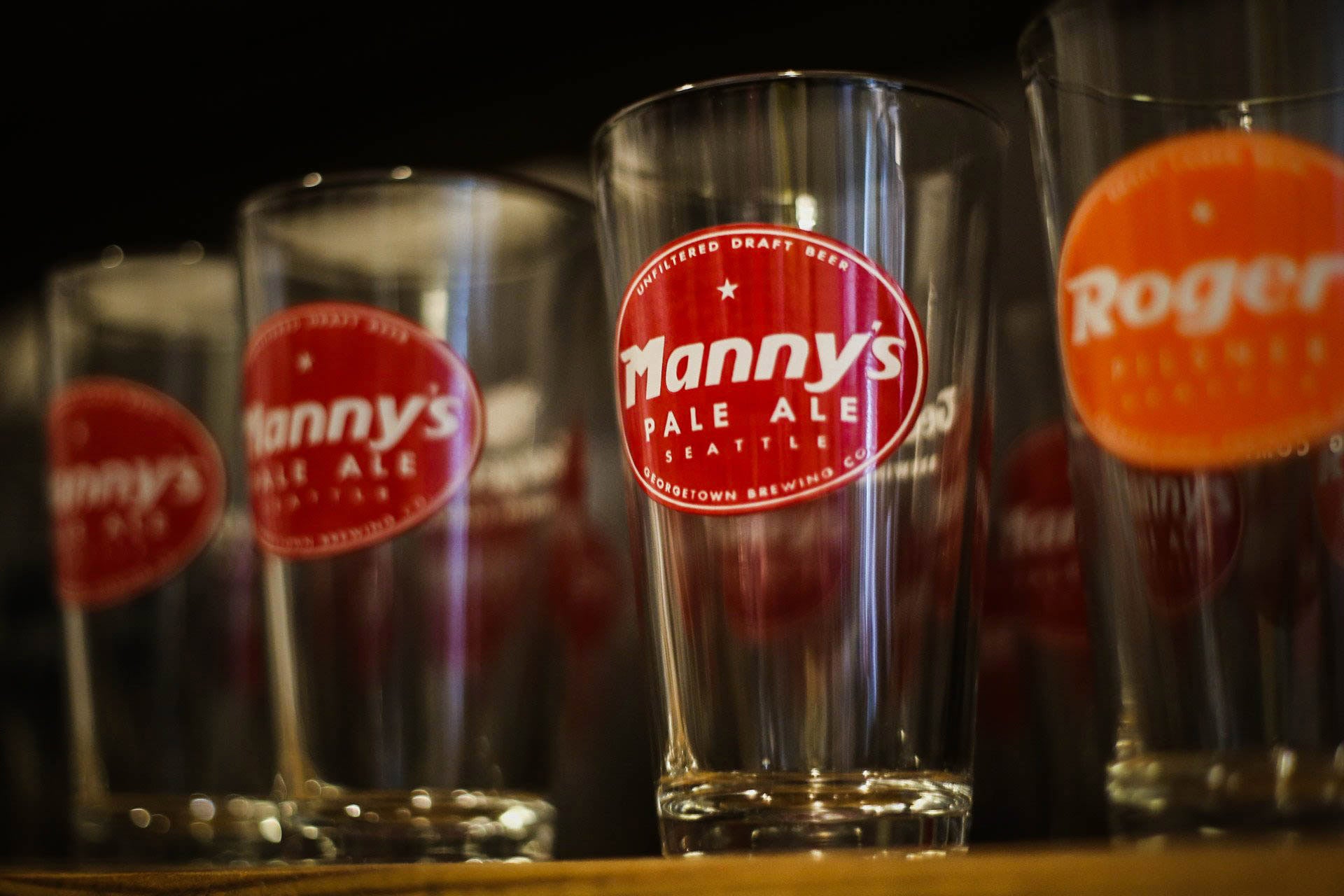 pint glasses with manny's and roger's logos lined up for sale