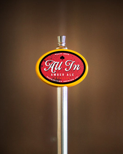 Photo of tap handle featuring All In Amber Ale logo